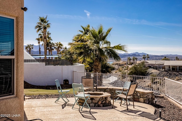 view of patio / terrace featuring an outdoor fire pit, fence, and a mountain view