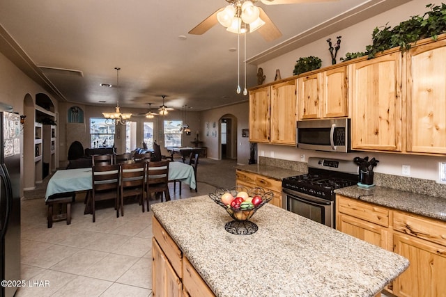 kitchen with arched walkways, light tile patterned floors, appliances with stainless steel finishes, open floor plan, and light brown cabinets