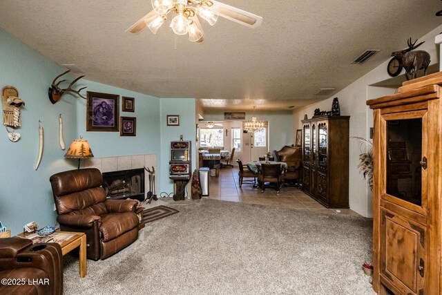 carpeted living room featuring a fireplace, ceiling fan with notable chandelier, and a textured ceiling