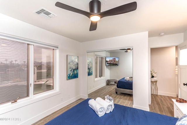 bedroom with visible vents, wood finished floors, a closet, baseboards, and ceiling fan