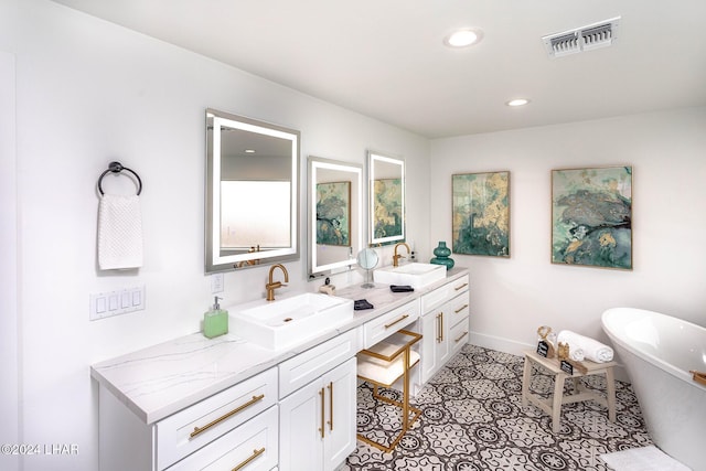 bathroom with a sink, visible vents, a freestanding bath, and double vanity