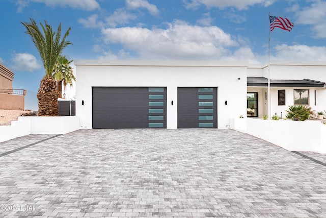 contemporary home with stucco siding, decorative driveway, and a garage