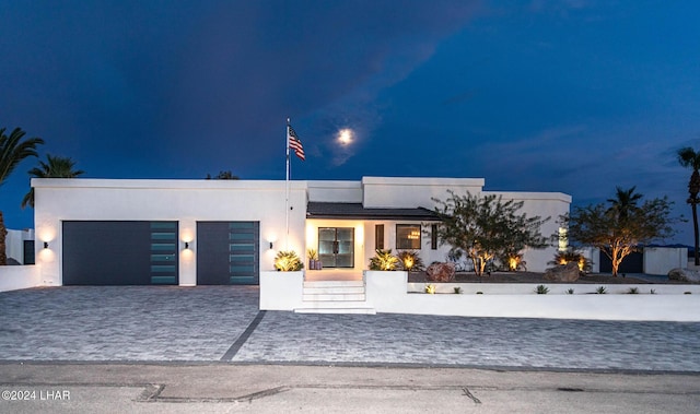 contemporary home featuring stucco siding, decorative driveway, and a garage