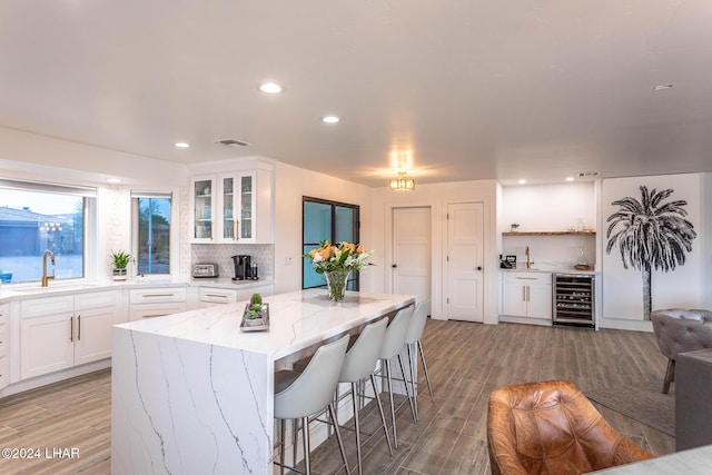 kitchen with beverage cooler, visible vents, a sink, backsplash, and a center island