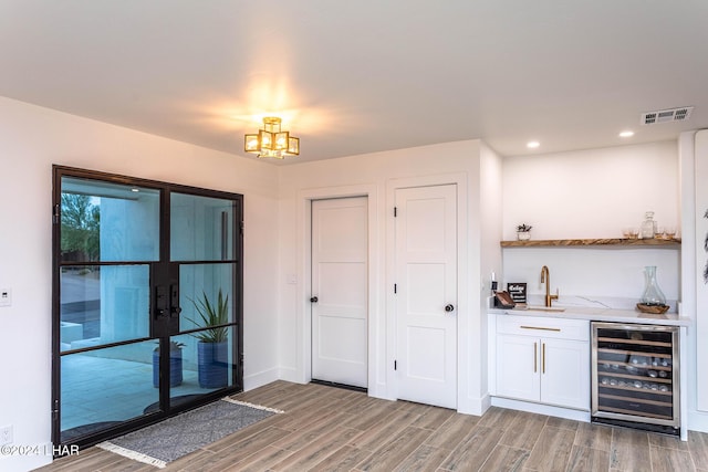 bar with wine cooler, visible vents, wet bar, and light wood-style floors