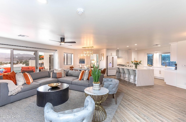 living area with recessed lighting, ceiling fan with notable chandelier, visible vents, and light wood-type flooring