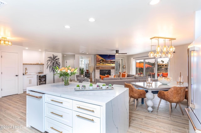 kitchen with ceiling fan, beverage cooler, a sink, and white cabinetry