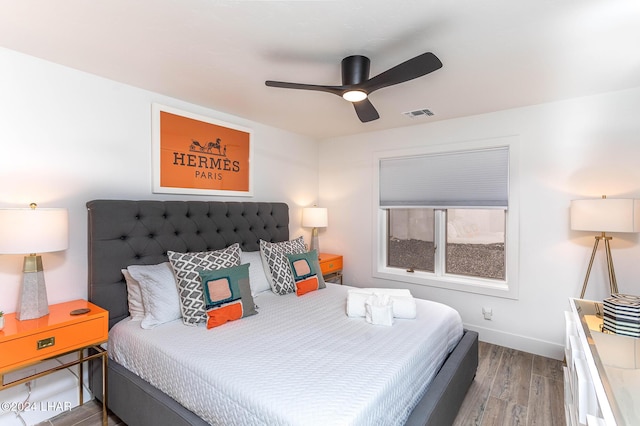 bedroom with visible vents, baseboards, wood finished floors, and a ceiling fan