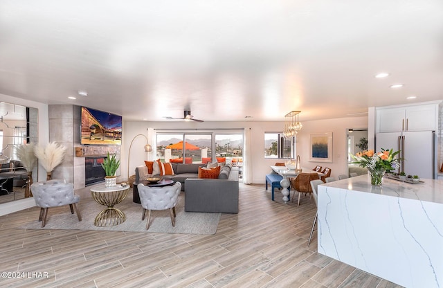 living area with recessed lighting, a notable chandelier, a large fireplace, and light wood-style floors