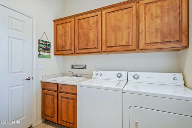 laundry area featuring washing machine and dryer, cabinet space, and a sink