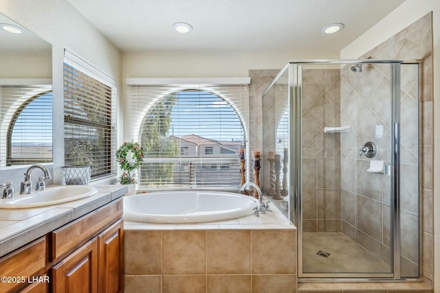 bathroom featuring a stall shower, recessed lighting, a bath, and vanity