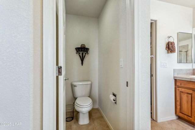 bathroom with toilet, vanity, baseboards, and tile patterned floors