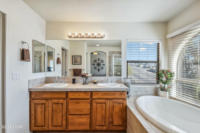 full bath with a garden tub, double vanity, and a sink