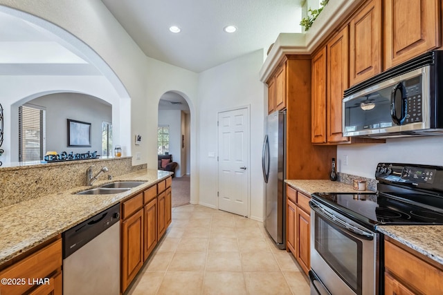 kitchen featuring light stone counters, stainless steel appliances, a sink, and light tile patterned flooring