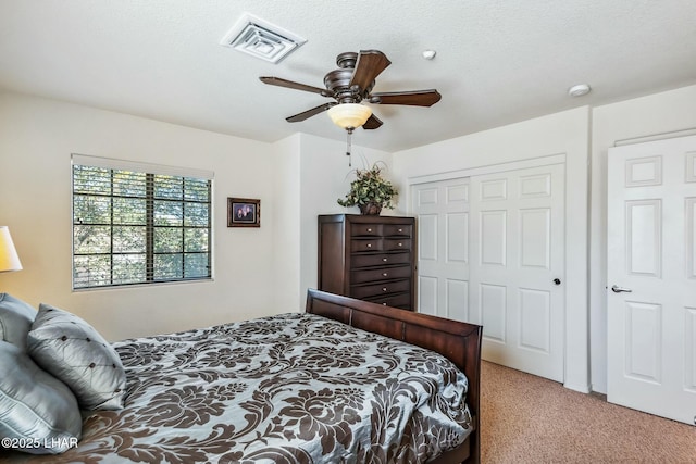 carpeted bedroom with a ceiling fan, a textured ceiling, visible vents, and a closet