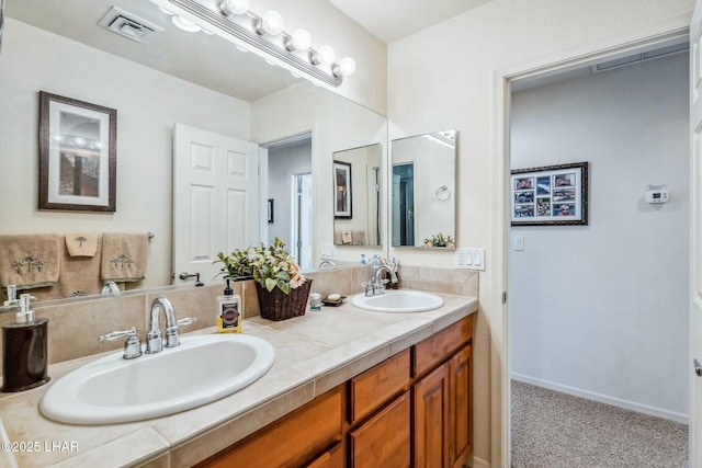 full bathroom with visible vents, a sink, baseboards, and double vanity