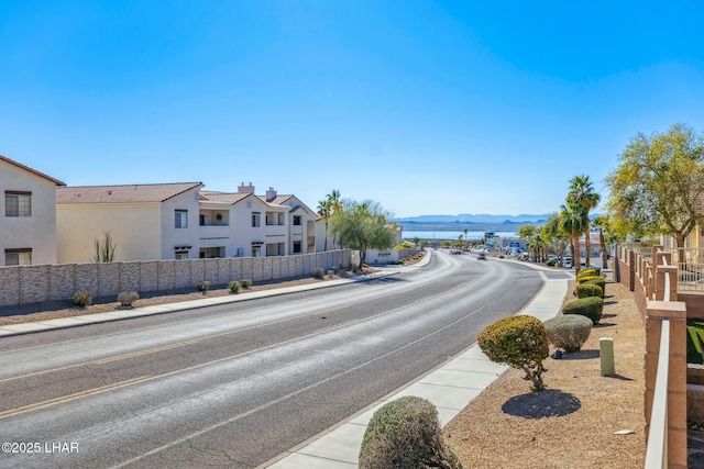 view of road featuring sidewalks, a residential view, a mountain view, and curbs