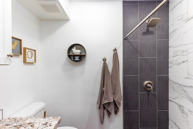 bathroom featuring vanity, toilet, and a tile shower