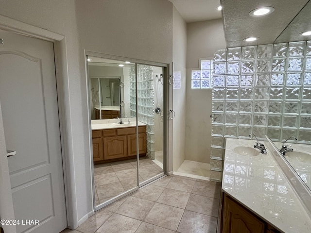 bathroom with tile patterned flooring, vanity, and walk in shower