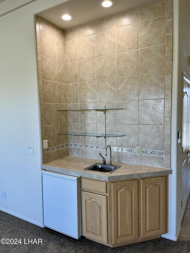 kitchen featuring dishwashing machine, light brown cabinetry, and sink