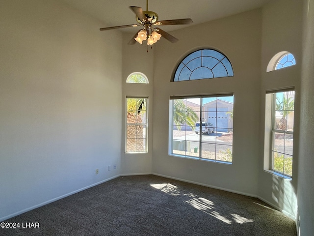 carpeted empty room with a high ceiling and ceiling fan