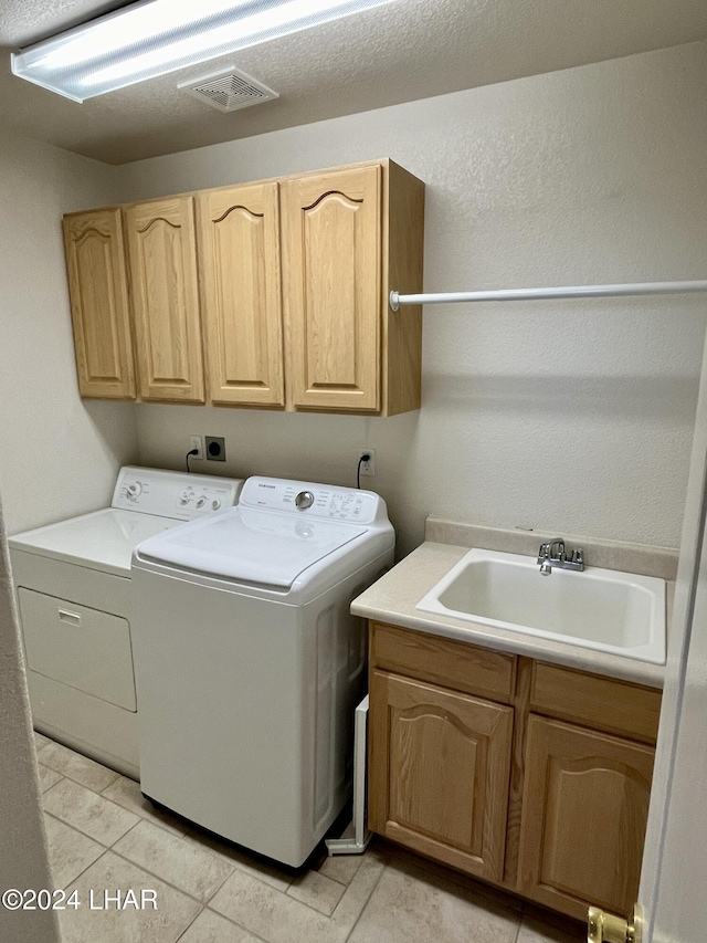 laundry area with cabinets, sink, light tile patterned floors, and washing machine and clothes dryer