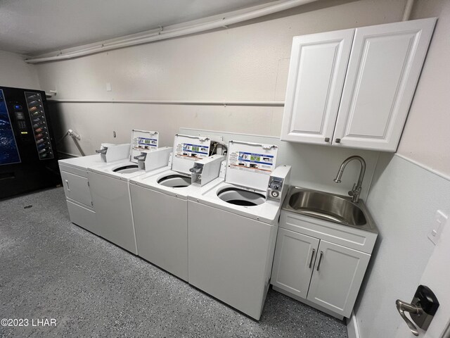 clothes washing area with cabinets, washer and clothes dryer, and sink