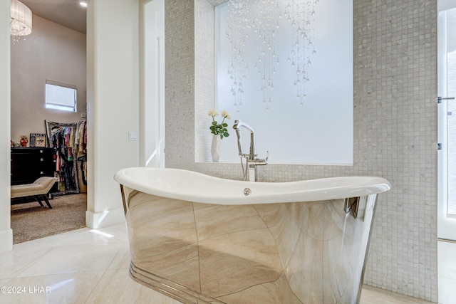 bathroom featuring a freestanding bath, a spacious closet, and tile patterned floors