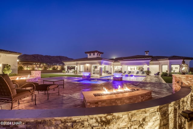 pool at twilight featuring a patio area, an outdoor fire pit, and an outdoor pool