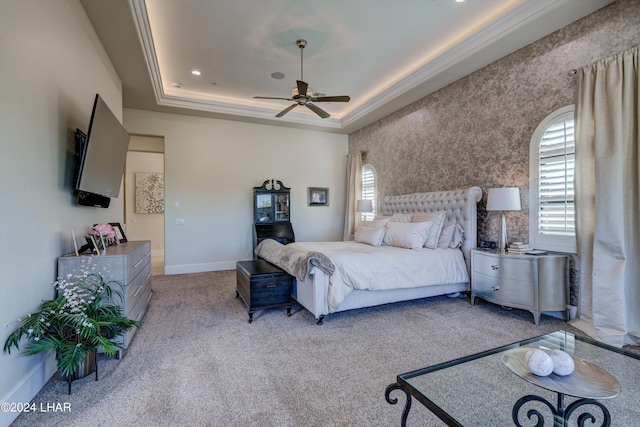 carpeted bedroom with ceiling fan, a raised ceiling, and baseboards