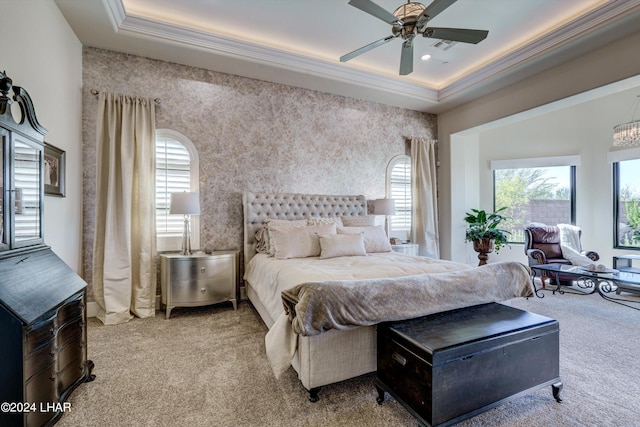 carpeted bedroom featuring multiple windows, a raised ceiling, a ceiling fan, and crown molding