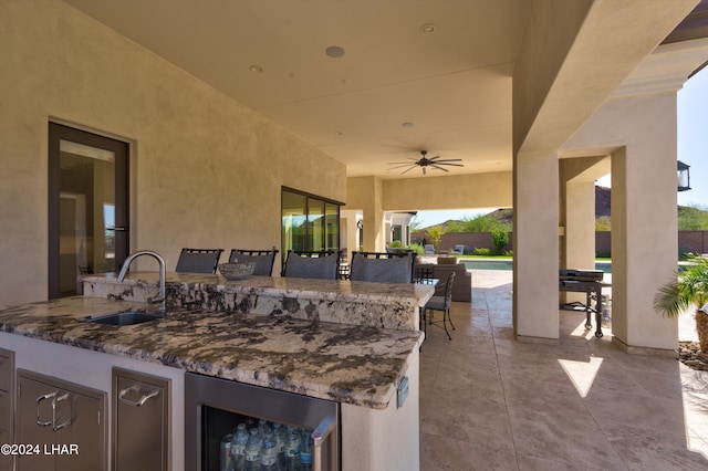 view of patio with a ceiling fan, outdoor wet bar, beverage cooler, and a sink