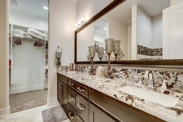 bathroom with a sink, a spacious closet, baseboards, and double vanity