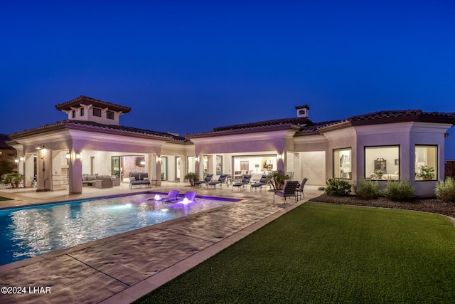 pool at night with a patio area, outdoor lounge area, and an outdoor pool