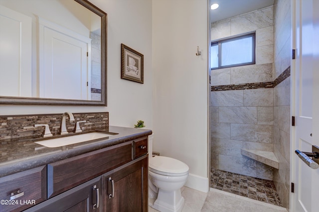 bathroom with tasteful backsplash, tiled shower, vanity, and toilet