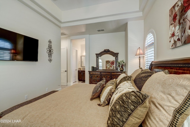 carpeted bedroom featuring ensuite bath, visible vents, and baseboards