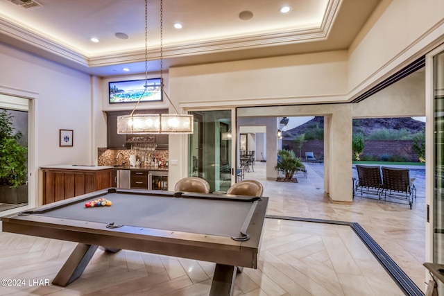 playroom with ornamental molding, wet bar, a high ceiling, and a tray ceiling