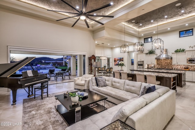 living area featuring an inviting chandelier, a high ceiling, a tray ceiling, and recessed lighting