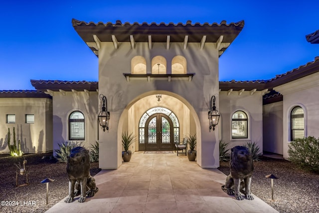 entrance to property with stucco siding, a tiled roof, and french doors