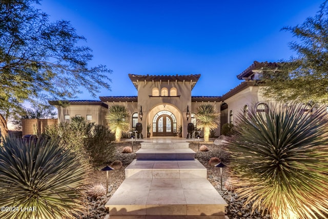 view of front facade featuring stucco siding, a tiled roof, and french doors