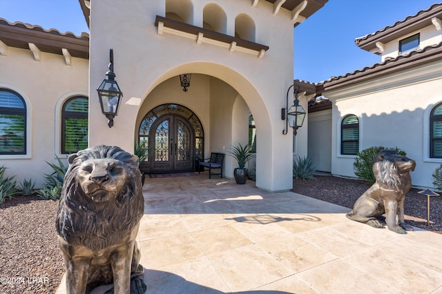 doorway to property with french doors, a tile roof, and stucco siding