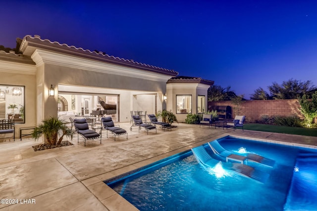 pool at night featuring an outdoor living space, a patio area, fence, and a fenced in pool