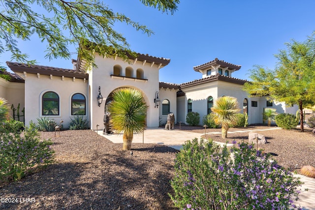 mediterranean / spanish-style home with driveway, a tiled roof, and stucco siding