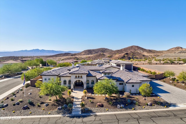 mediterranean / spanish-style house with a tiled roof, decorative driveway, a mountain view, and stucco siding