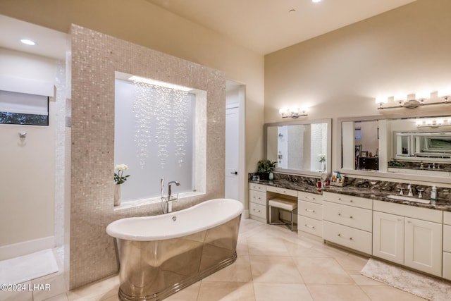 bathroom featuring tile patterned flooring, a freestanding bath, and vanity