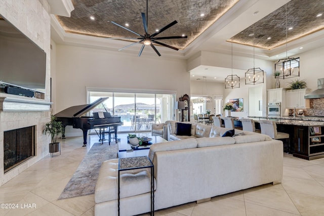 living room featuring a fireplace, light tile patterned floors, recessed lighting, a raised ceiling, and a high ceiling