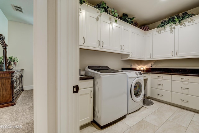 clothes washing area with visible vents, cabinet space, washer and clothes dryer, and light tile patterned floors