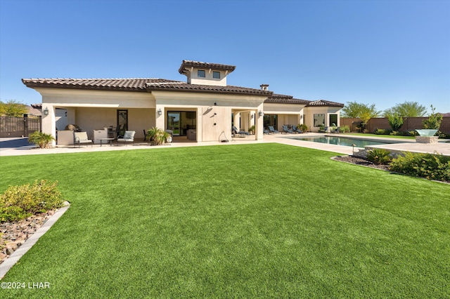 rear view of property featuring a patio, a lawn, and fence