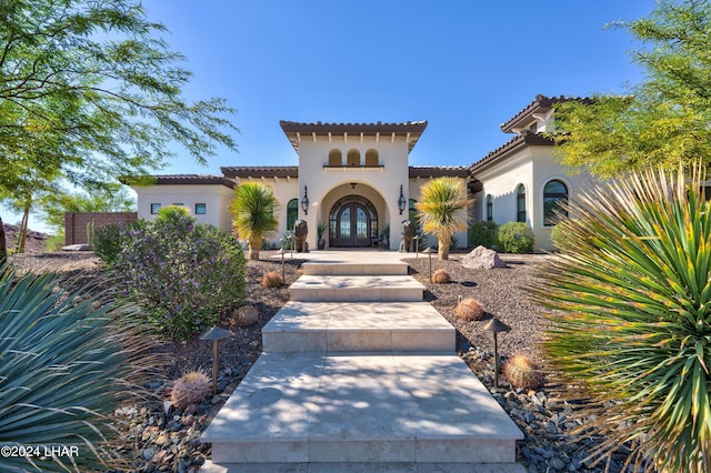 property entrance featuring stucco siding, a tile roof, and french doors