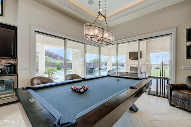 game room featuring beverage cooler, billiards, ornamental molding, a brick fireplace, and a tray ceiling